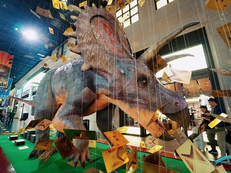 Animatronic dinosaur display attracting visitors in a shopping mall atrium