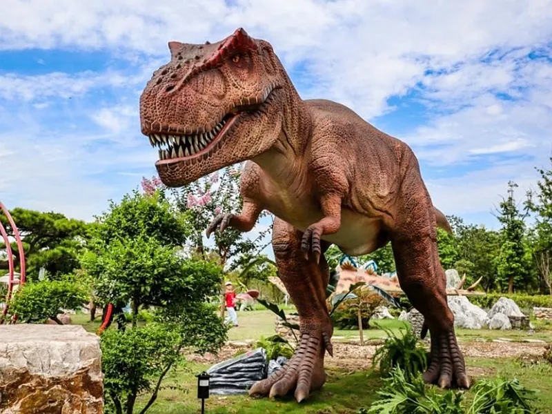 Outdoor animatronic dinosaur exhibit beside a zoo trail
